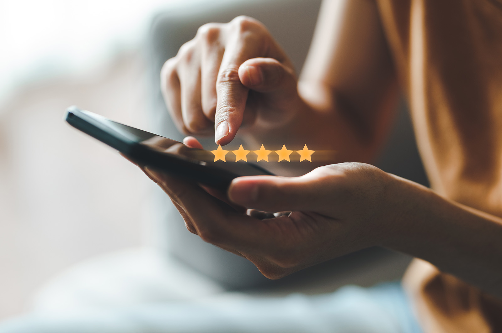 The image shows a person s hand holding a smartphone with a five-star rating icon displayed on the screen, suggesting a positive review or rating for a product or service.