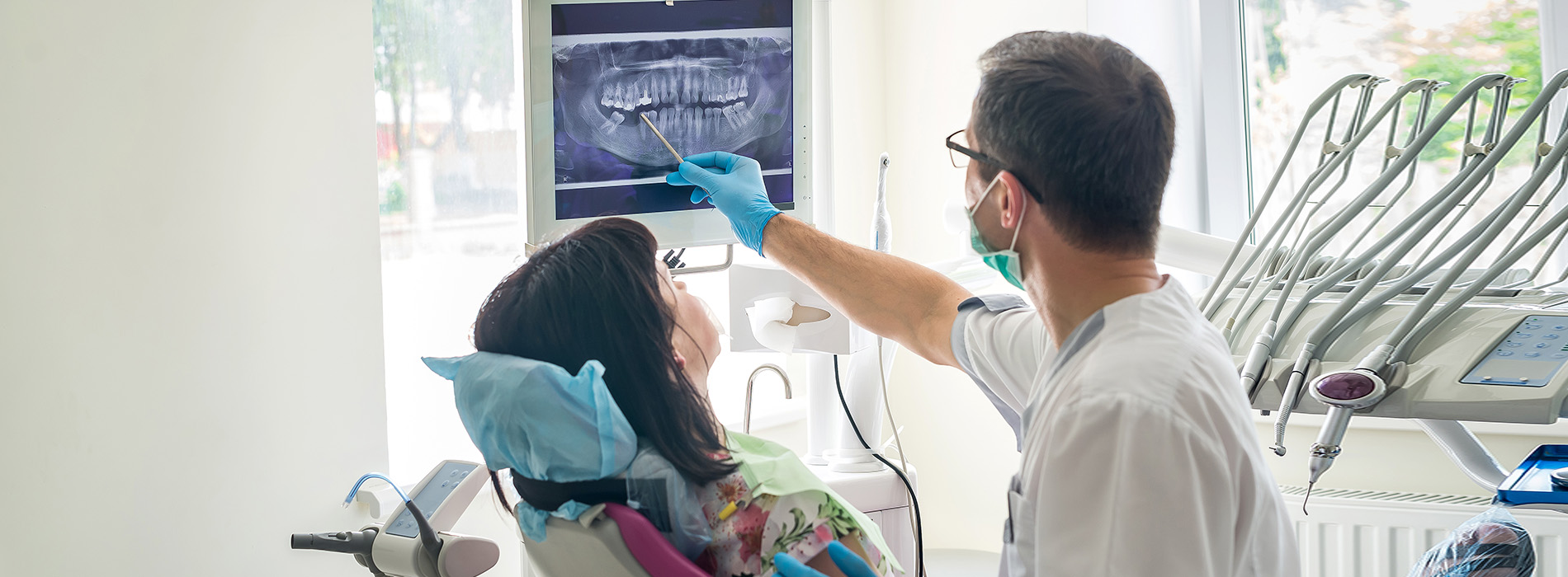 A dental professional is assisting a patient in a dental chair.