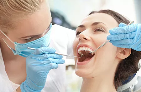Dental hygienist performing teeth cleaning procedure on patient in dental office.