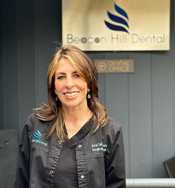 The image shows a person standing in front of a building with the sign  Beacon Hill Dental Office  on it.