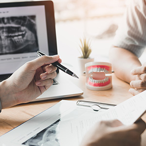 A person writing on a tablet with an X-ray image displayed, while another person takes notes and looks at the tablet.