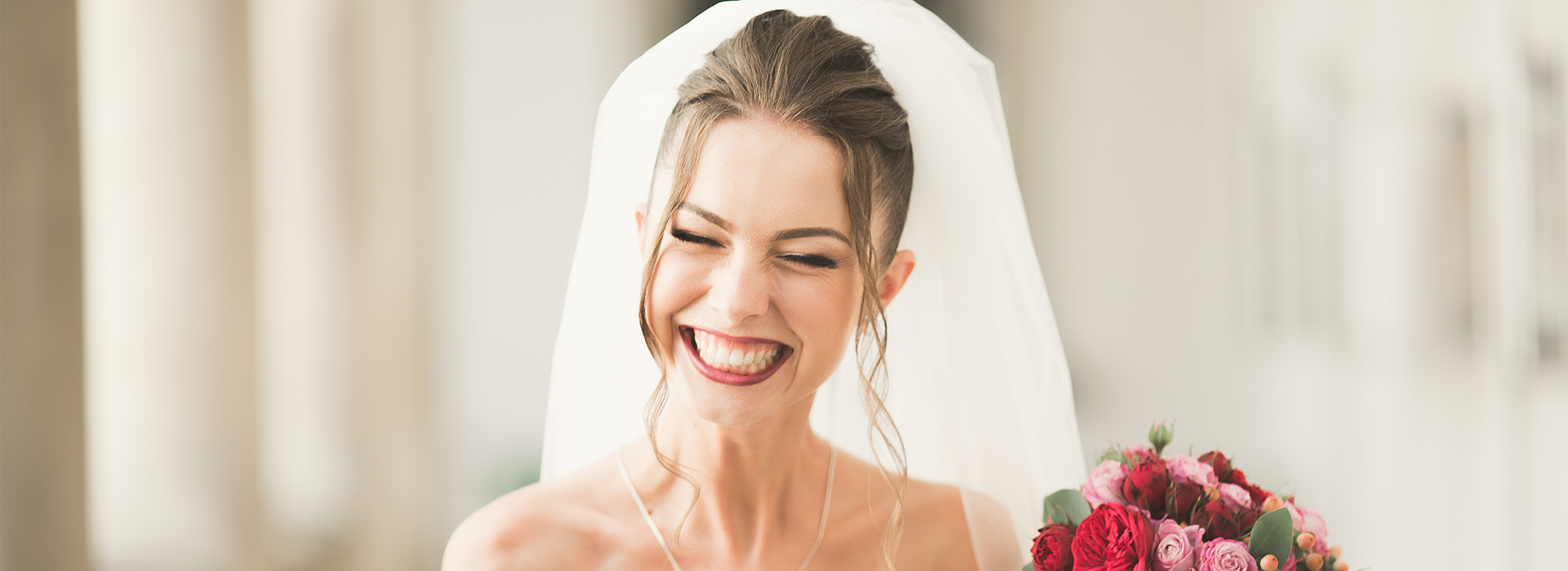 The image is a photograph of a bride and groom at their wedding, with the woman smiling and wearing a traditional white bridal gown, and the man in a suit.