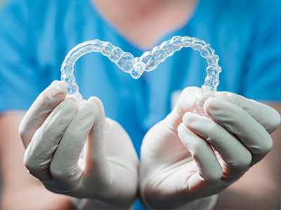 A dental professional holding a transparent heart-shaped object, symbolizing love or support for oral health.