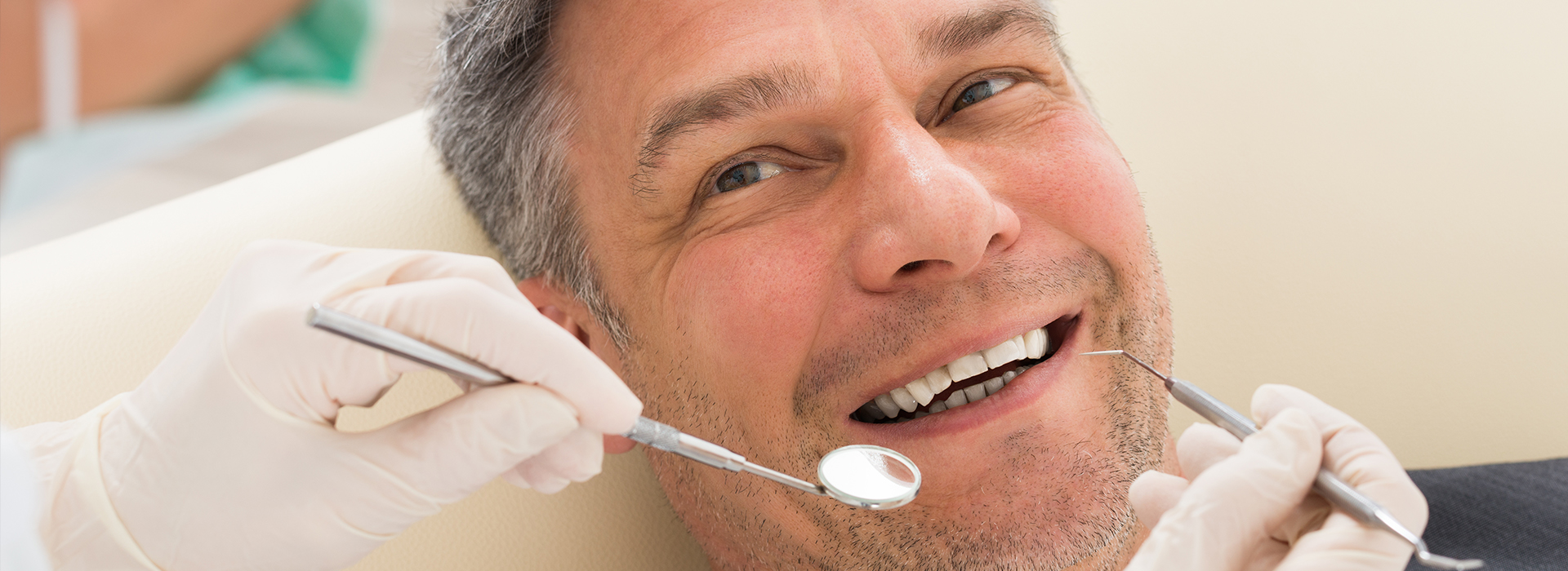 A man in a dental chair receiving dental care, with a dentist working on his teeth.