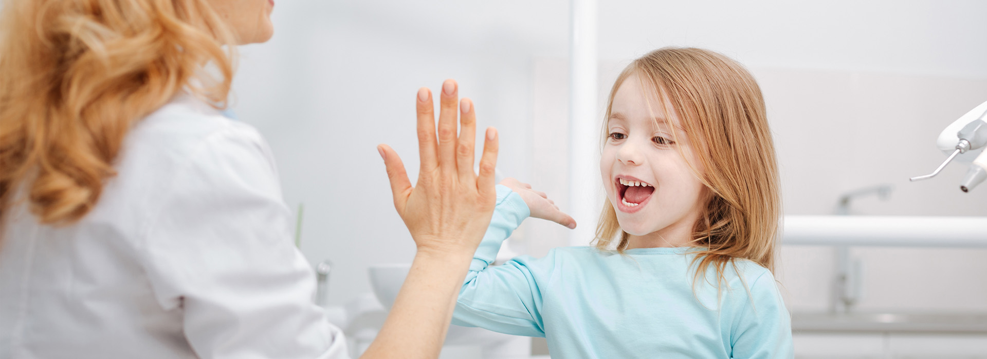 A woman and a young girl interacting in a bathroom setting.