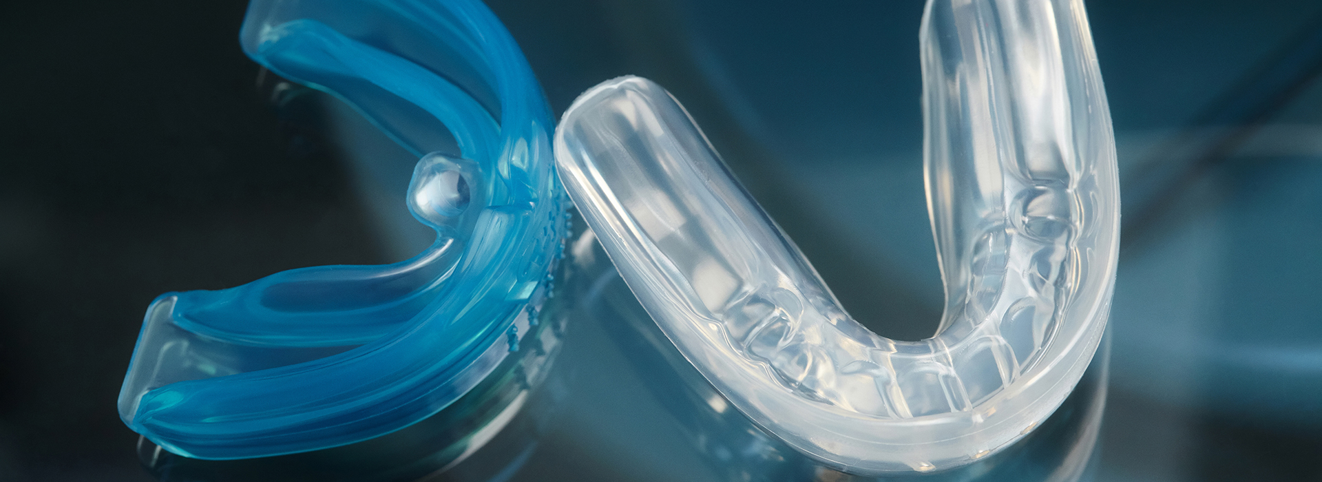 The image displays a pair of blue, translucent dental retainers against a dark background.