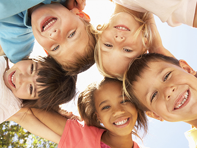 A group of children smiling and huddled together for a photo.