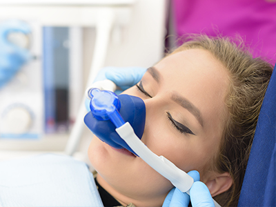 A woman receiving oxygen therapy with a medical device, attended by a healthcare professional.